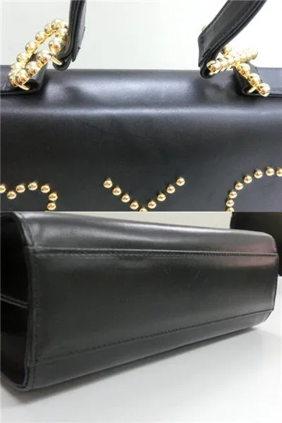 Vintage MOSCHINO black leather handbag in classic kelly purse style with golden studded heart, X, and O, playful motifs. Perfect daily bag